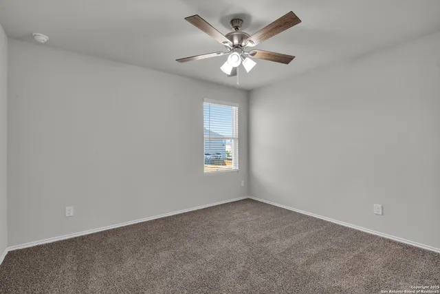 an empty room with a chandelier fan and windows