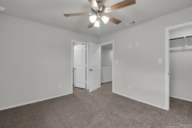 a view of an empty room and a ceiling fan