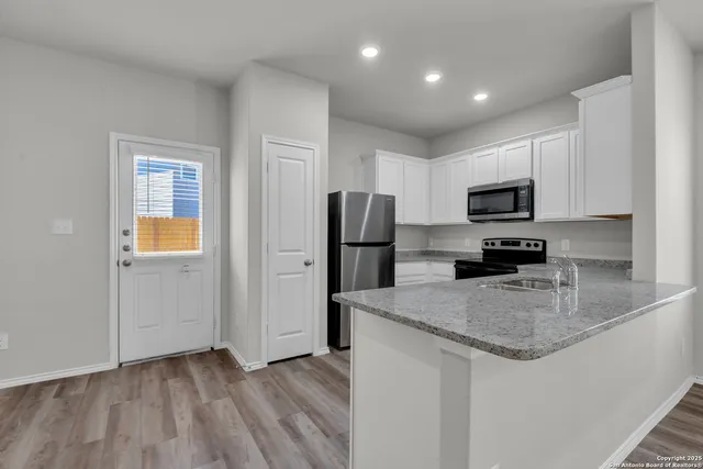 a kitchen with a refrigerator a microwave a sink and cabinets