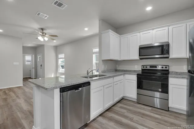 a kitchen with stainless steel appliances a stove sink microwave and cabinets