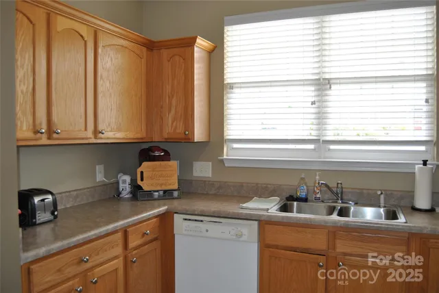 a kitchen with stainless steel appliances granite countertop a sink a window and white cabinets