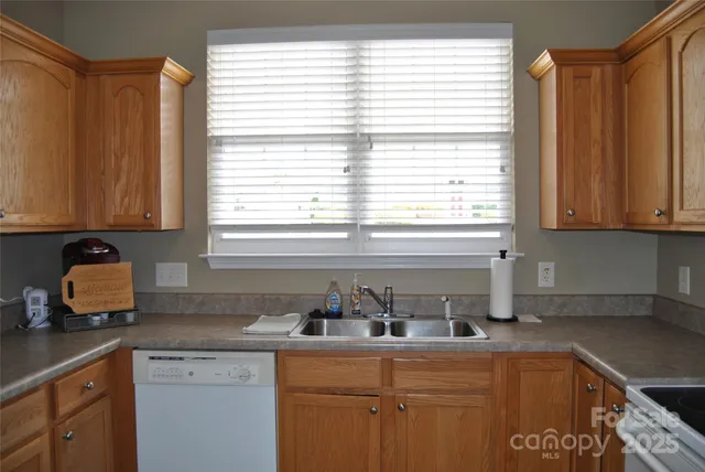 a kitchen with stainless steel appliances granite countertop a sink a window and a counter space