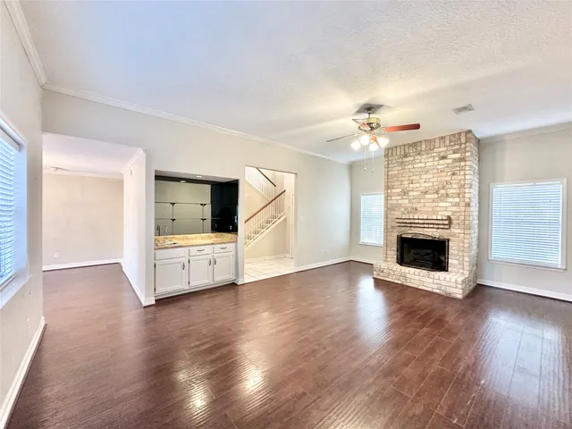 a view of a livingroom with a fireplace a ceiling fan and windows