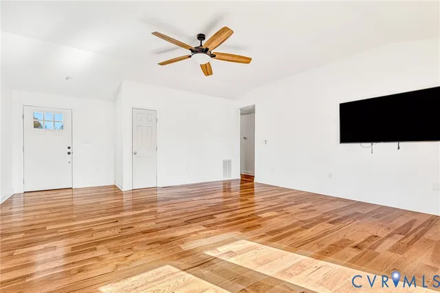 a view of empty room with wooden floor and ceiling fan