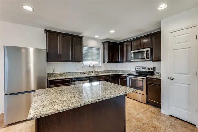 a kitchen with stainless steel appliances granite countertop a refrigerator stove microwave and sink
