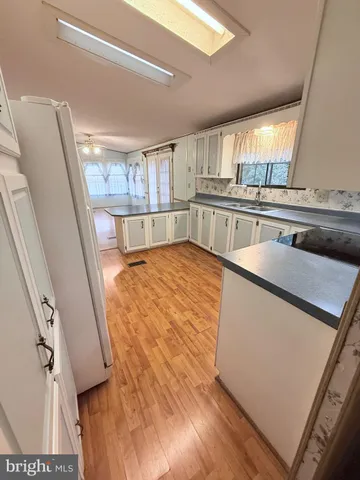 a view of a kitchen with kitchen island a sink wooden floor and a counter top space