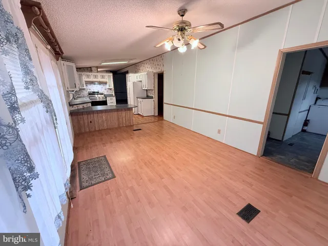 a view of a refrigerator in kitchen and an empty room