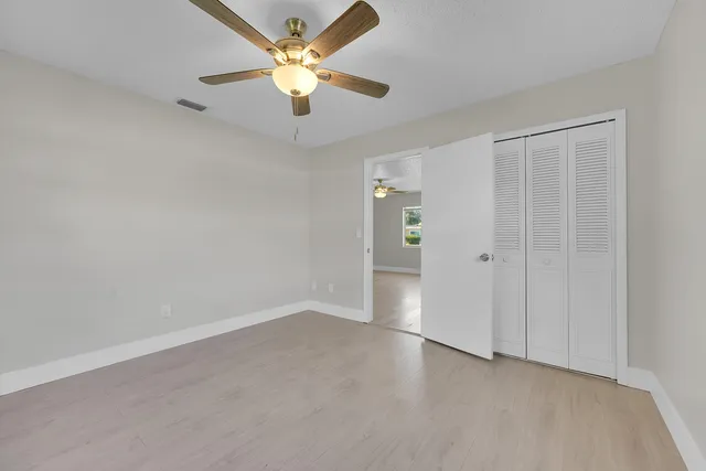 an empty room with closet and a ceiling fan