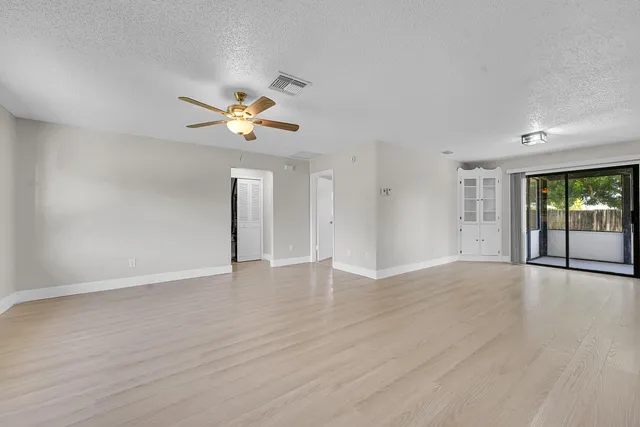 a view of an empty room with window and wooden floor