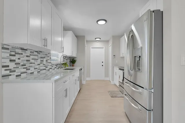 a bathroom with a granite countertop sink mirror and refrigerator