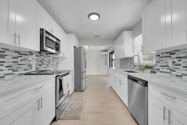 a large kitchen with stainless steel appliances kitchen island granite countertop a stove refrigerator and cabinets