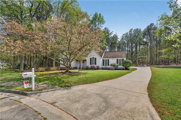 a view of a house next to a big yard and large trees