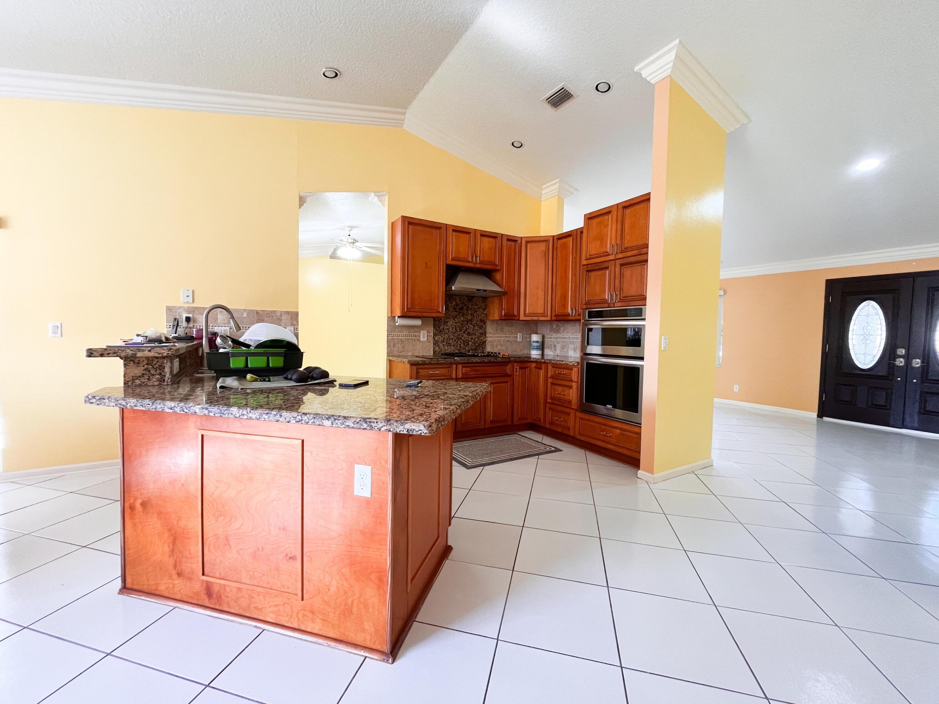 1305 Monteray Way Greenacres, FL 33413 - Photo 17 of 29 a kitchen with stainless steel appliances granite countertop a refrigerator and a stove