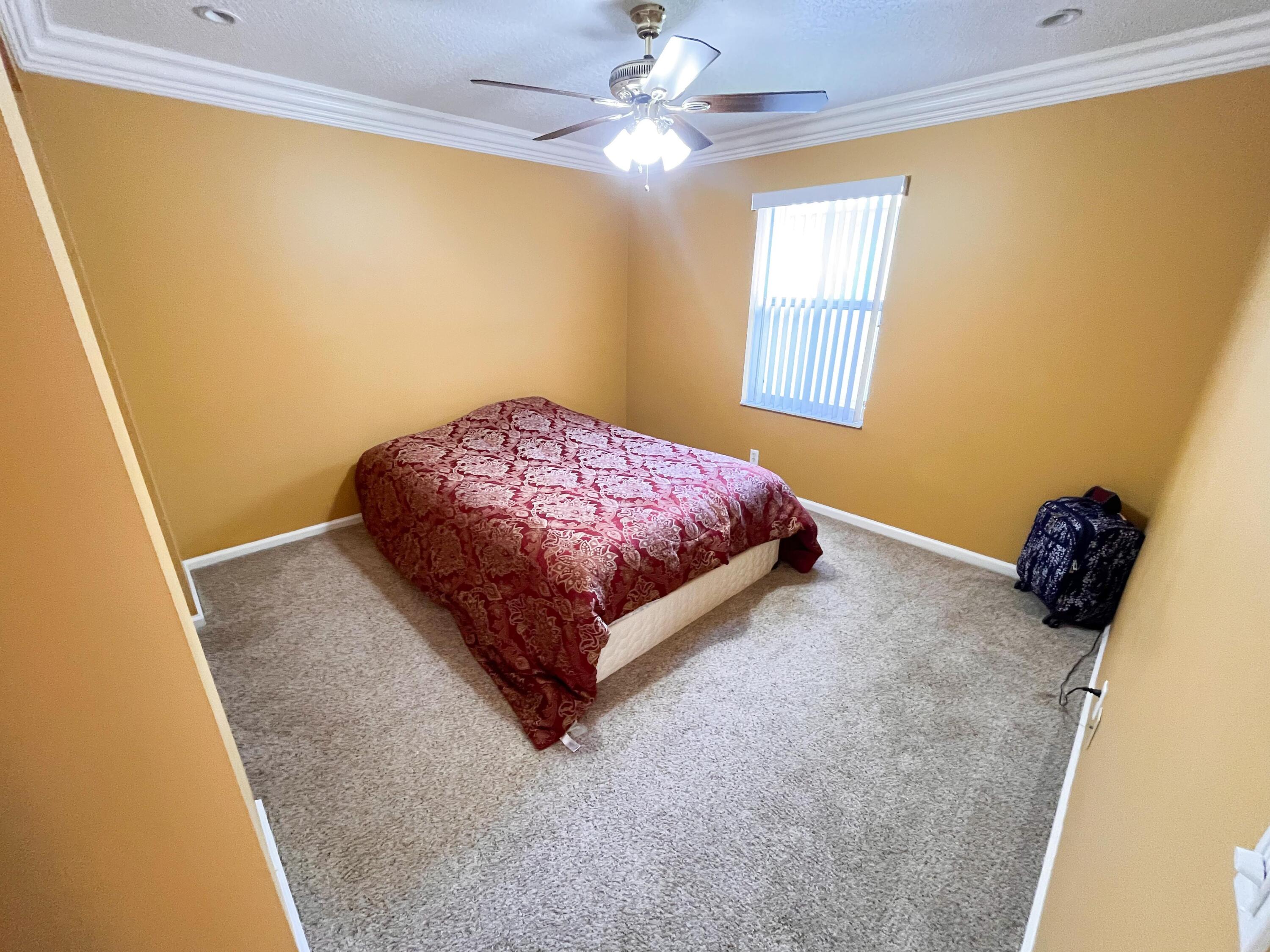 1305 Monteray Way Greenacres, FL 33413 - Photo 21 of 29 a spacious bedroom with a bed and a chandelier