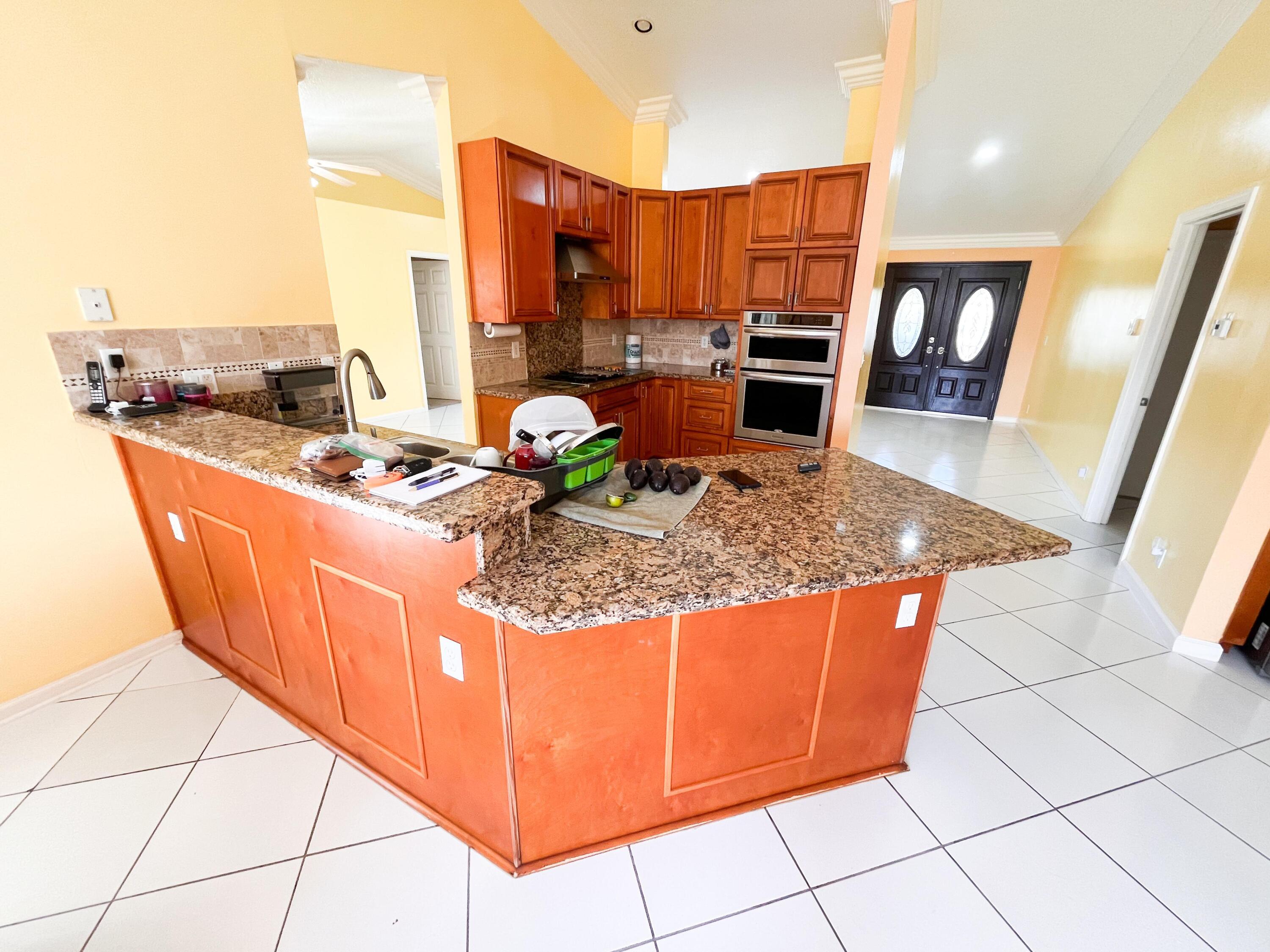 1305 Monteray Way Greenacres, FL 33413 - Photo 23 of 29 a kitchen with stainless steel appliances granite countertop a stove a sink and a microwave