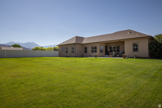 4635 East Sunny Acres Lane Moab, UT 84532 - Photo 20 of 56 Expansive green lawn bordering a stucco exterior with multiple windows and a covered patio
