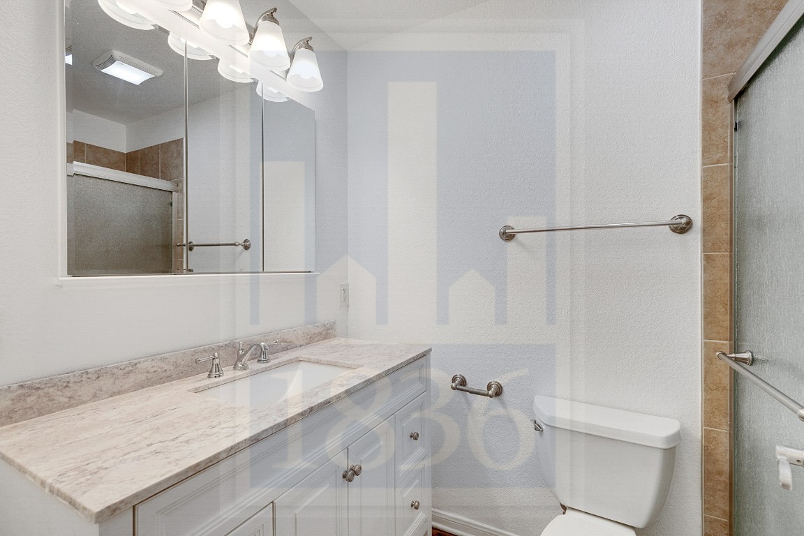 4622 Credo Lane, Unit 167 Austin, TX 78725 - Photo 14 of 25 a bathroom with a granite countertop sink a toilet and shower