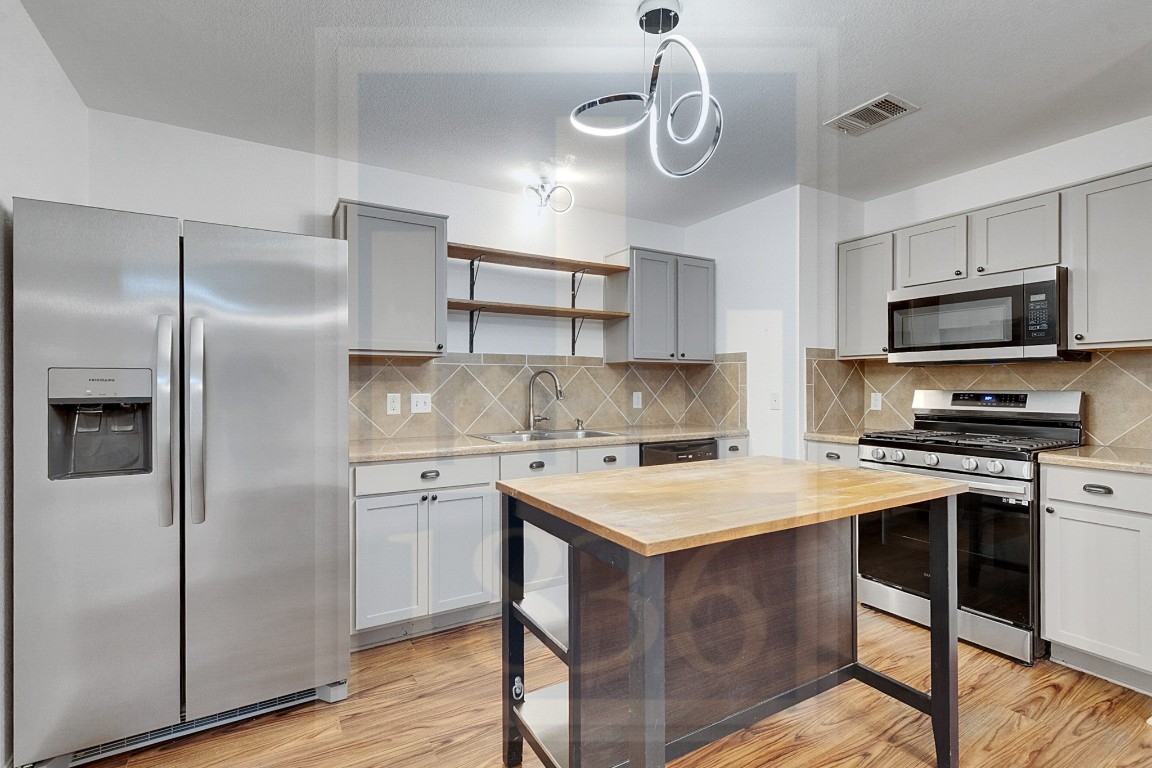 4622 Credo Lane, Unit 167 Austin, TX 78725 - Photo 4 of 25 a kitchen with stainless steel appliances a stove a sink island and refrigerator