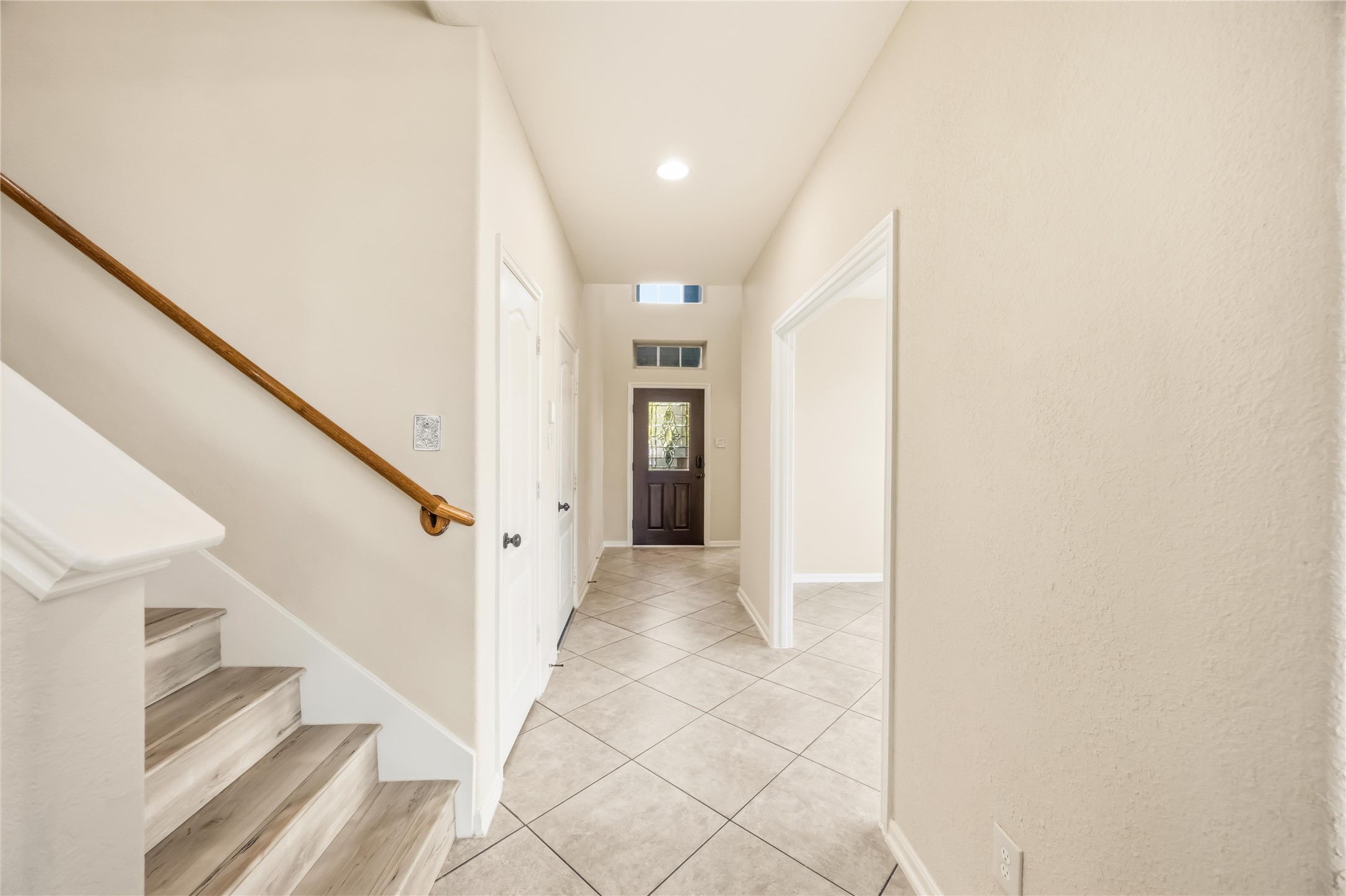 17206 Upper Ridge Lane Humble, TX 77346 - Photo 3 of 33 Entryway / Foyer – Bright and inviting entry with high ceilings, tile flooring, and a staircase accented by a wood handrail.