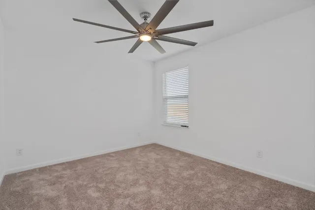 an empty room with a window and a fan