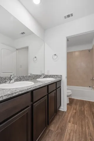 a bathroom with a granite countertop sink toilet and a large mirror