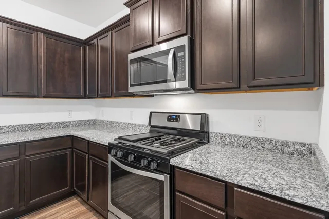 a kitchen with granite countertop stainless steel appliances a stove microwave and sink
