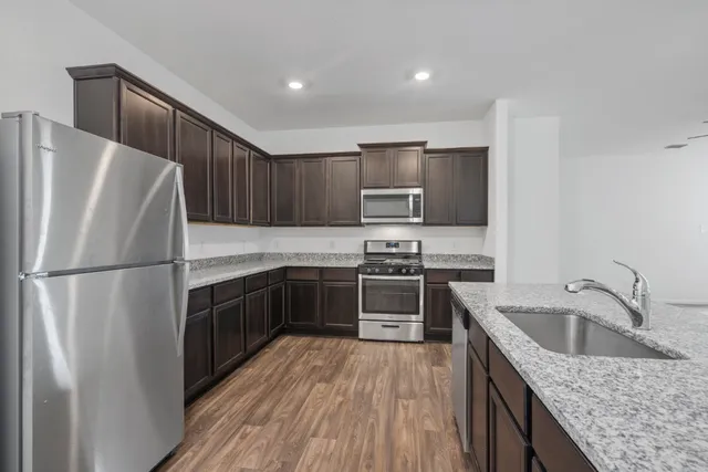a kitchen with a refrigerator sink and wooden cabinets