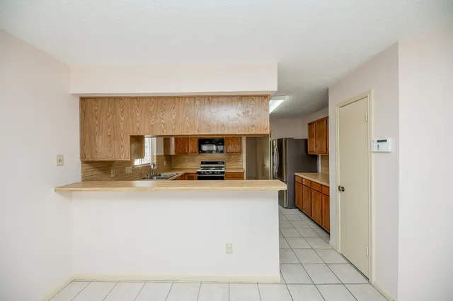a large kitchen with stainless steel appliances a sink a stove and cabinets