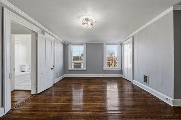 a view of an empty room with wooden floor and a window