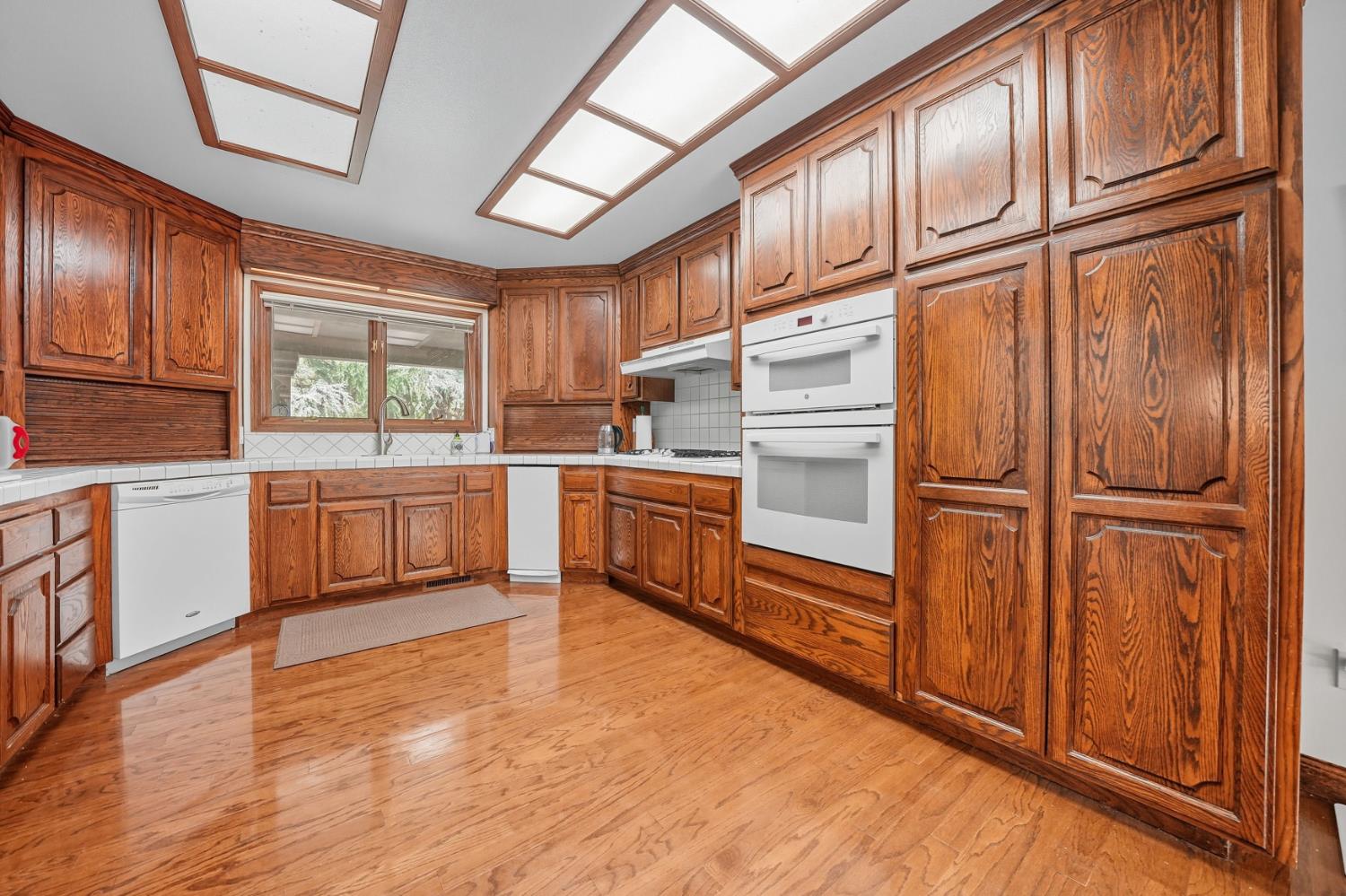 19491 East Clinton Road Jackson, CA 95642 - Photo 26 of 72 a kitchen with stainless steel appliances granite countertop a refrigerator a sink dishwasher and white cabinets with wooden floor