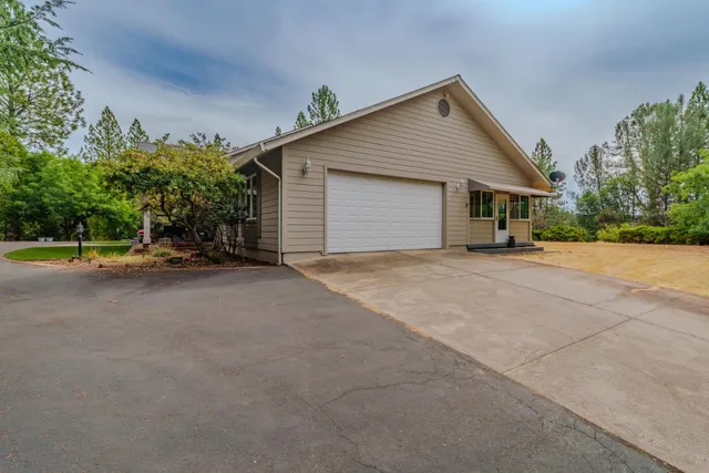 a view of a house with a yard and large tree