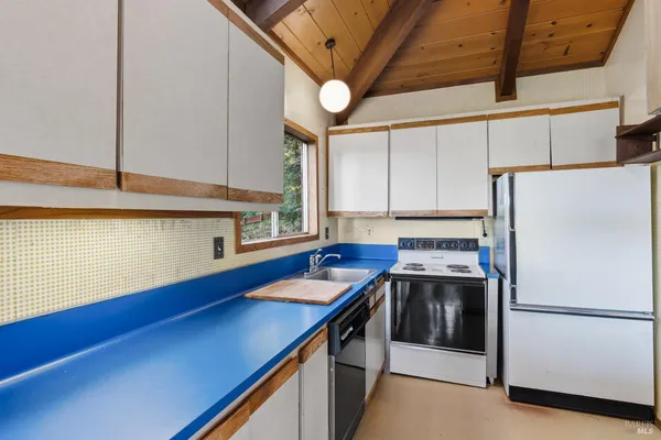 a kitchen with stainless steel appliances a refrigerator a sink and white cabinets