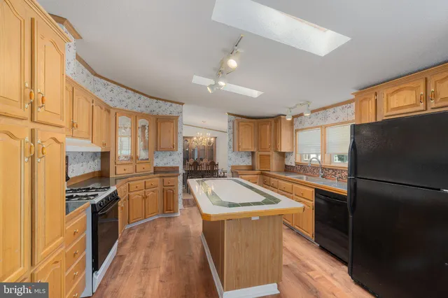 a kitchen with a refrigerator a kitchen island a sink and wooden floor