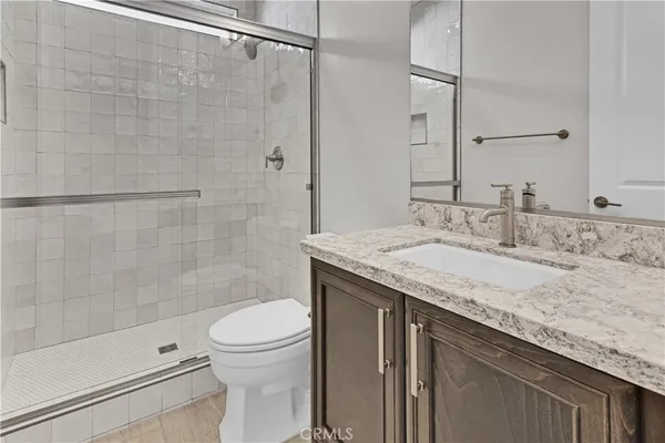 a bathroom with a granite countertop sink a toilet and shower