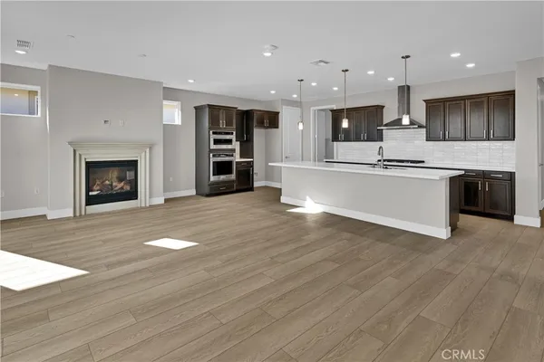 a view of kitchen with kitchen island a sink wooden floor and a fireplace