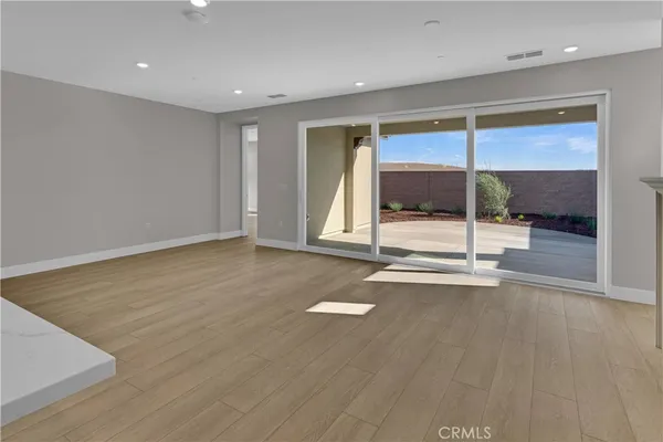 an empty room with wooden floor and glass door