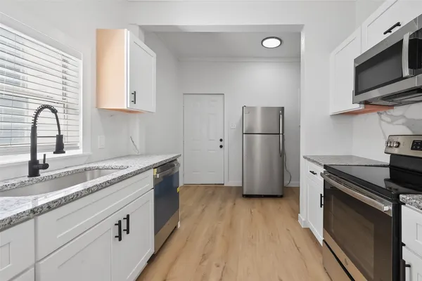 a kitchen with a sink wooden floor and stainless steel appliances
