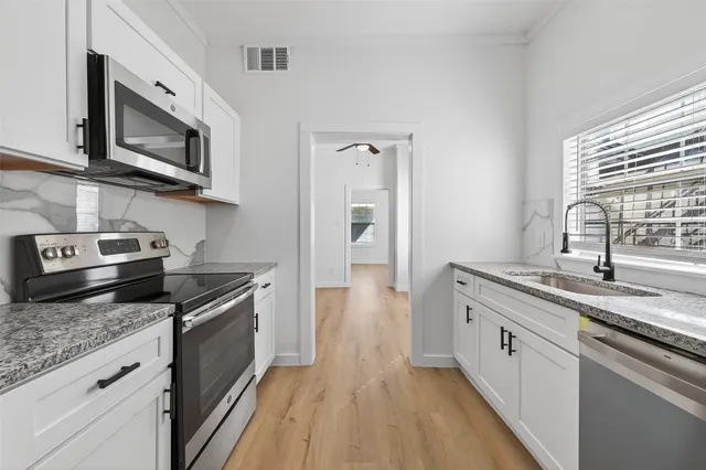 a kitchen with stainless steel appliances granite countertop a sink dishwasher stove and microwave with wooden floor