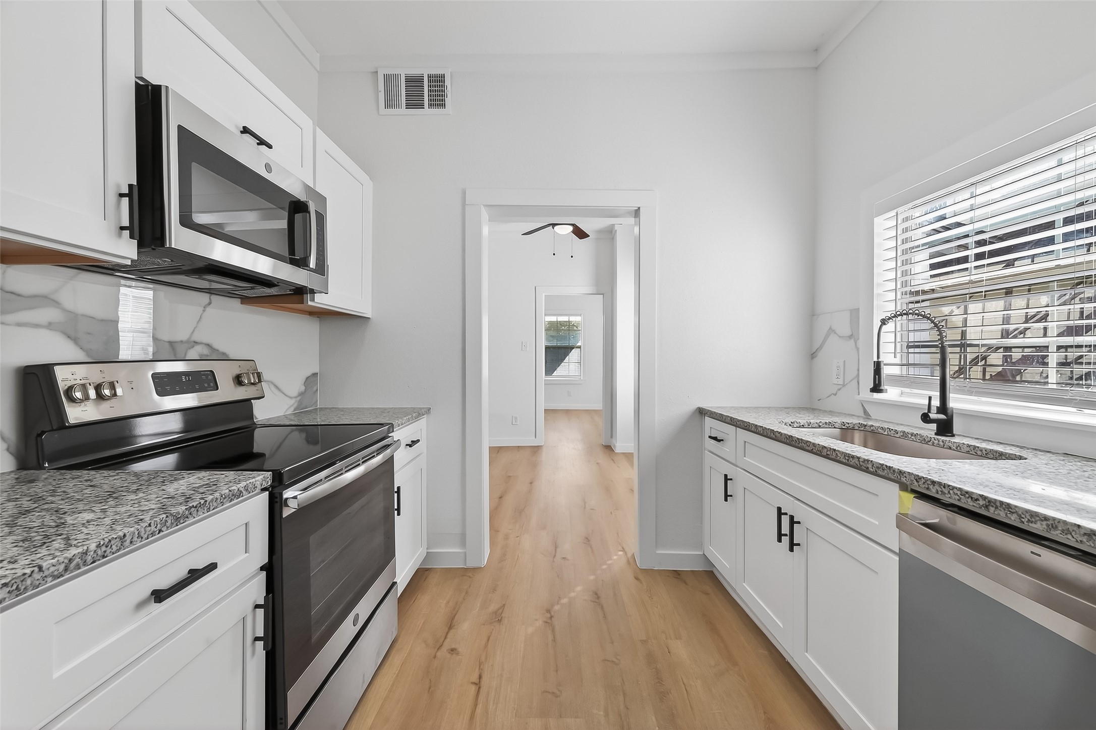 2202 Hutchins Street, Unit A Houston, TX 77003 - Photo 12 of 27 a kitchen with stainless steel appliances granite countertop a sink dishwasher stove and microwave with wooden floor