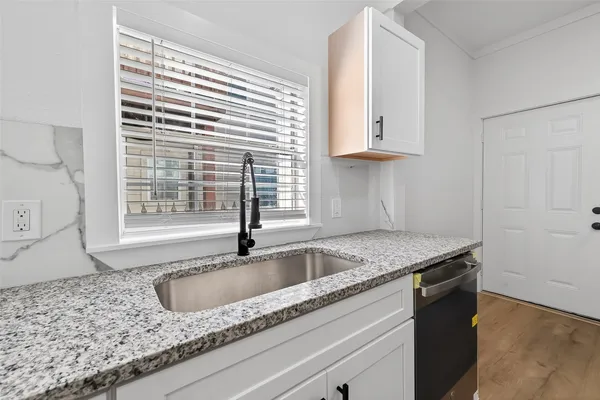a kitchen with granite countertop a sink and a white wooden cabinets