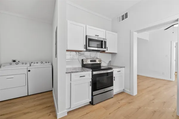a kitchen with cabinets stainless steel appliances and wooden floor