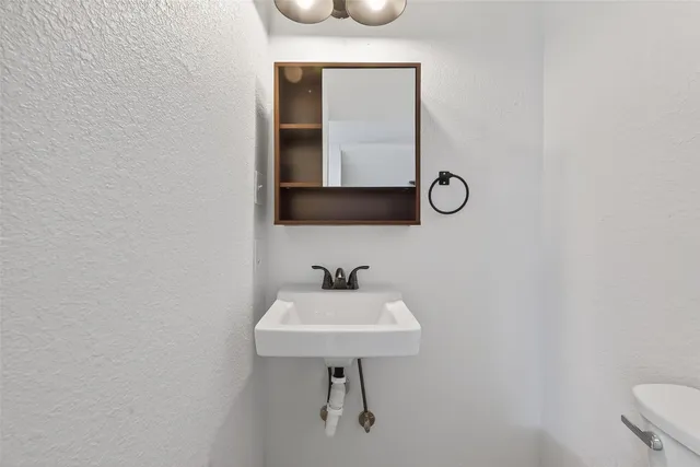 a bathroom with a sink a light fixture and a toilet