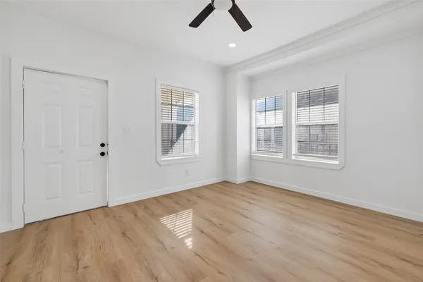 a view of an empty room with window and wooden floor