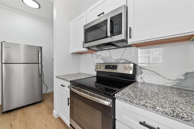 a kitchen with stainless steel appliances granite countertop a stove microwave and refrigerator