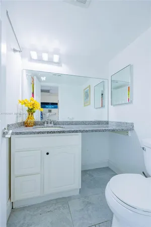 a bathroom with a granite countertop toilet sink and mirror