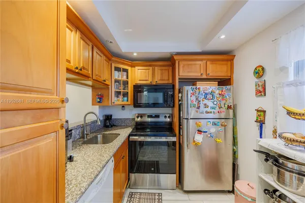 a kitchen with stainless steel appliances granite countertop a refrigerator a stove and a sink with wooden floor