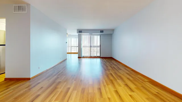 a view of empty room with wooden floor and fan