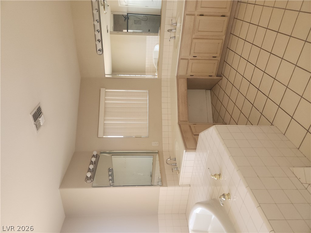 564 Ridgeway Road Henderson, NV 89015 - Photo 10 of 22 Dual vanities and a tiled bath create a functional and pleasant bathroom space.