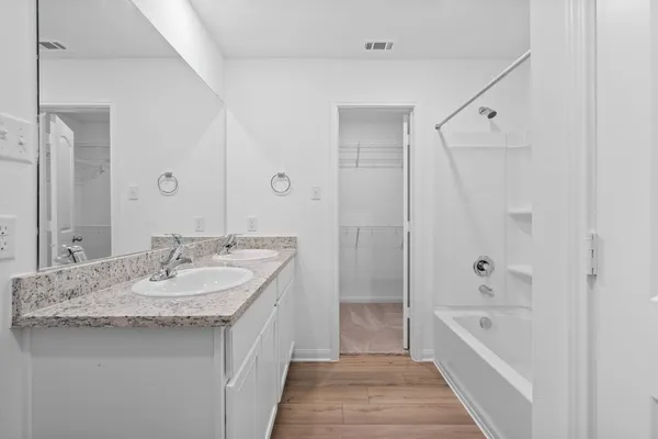 a bathroom with a granite countertop sink a mirror a bathtub and shower