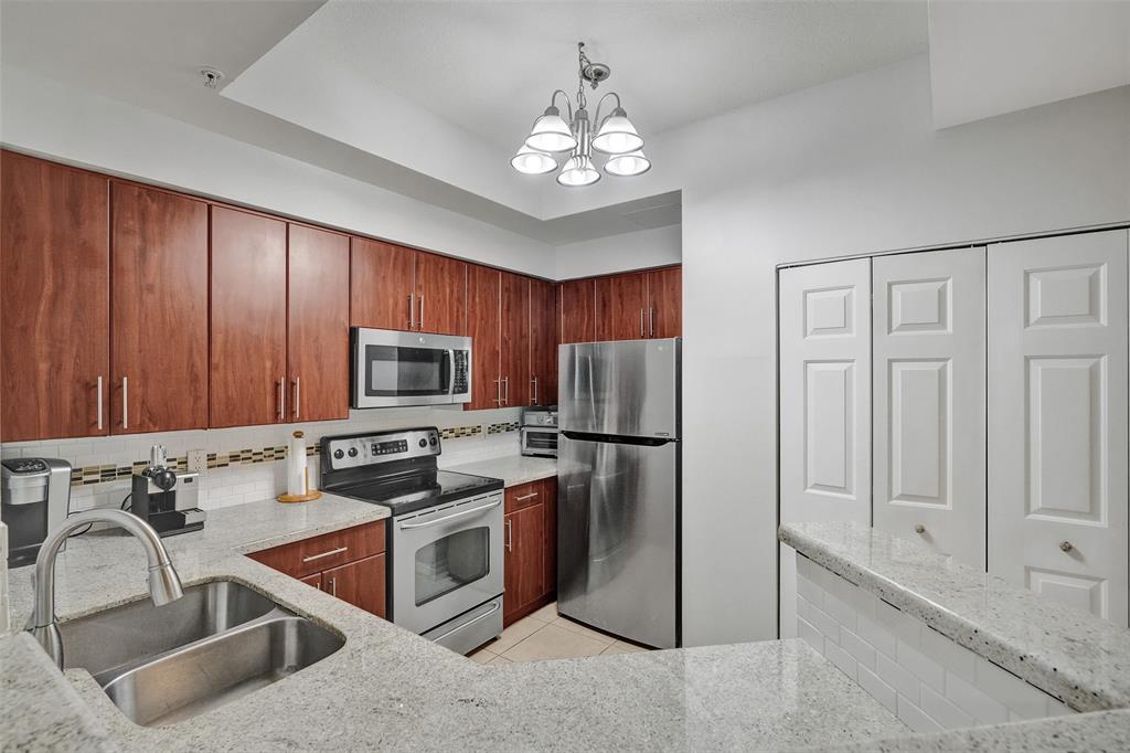 2421 Northeast 65th Street, Unit 2113 Fort Lauderdale, FL 33308 - Photo 8 of 45 a kitchen with stainless steel appliances granite countertop a refrigerator a sink a stove with cabinets